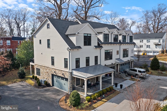 view of front of property featuring stone siding, a shingled roof, a residential view, and aphalt driveway