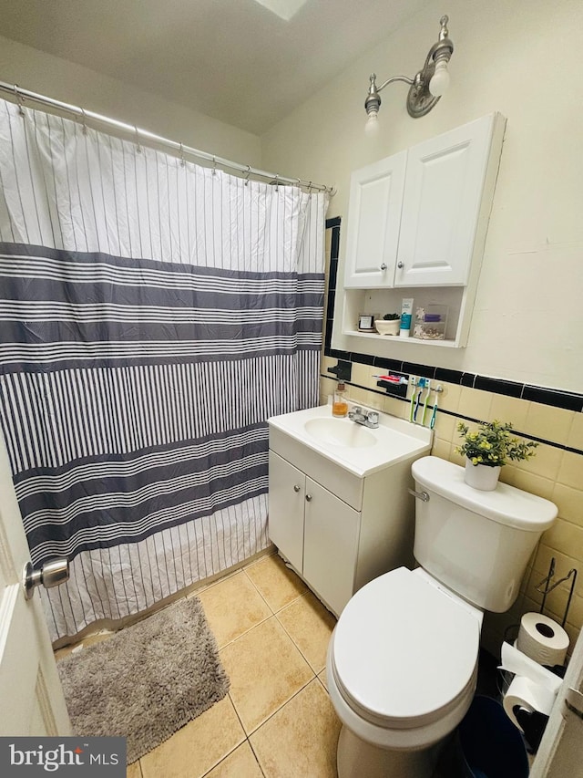 bathroom with toilet, tile walls, vanity, wainscoting, and tile patterned floors