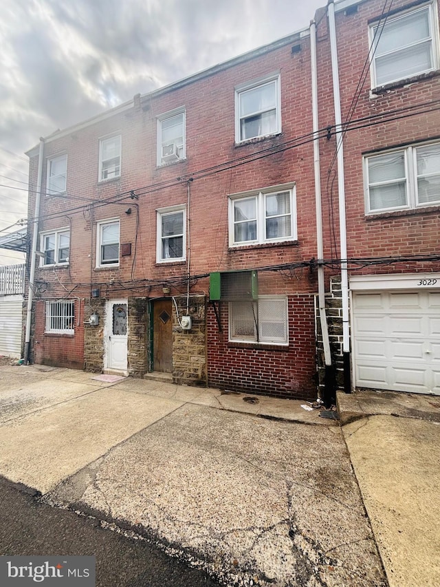 multi unit property featuring brick siding, driveway, and an attached garage