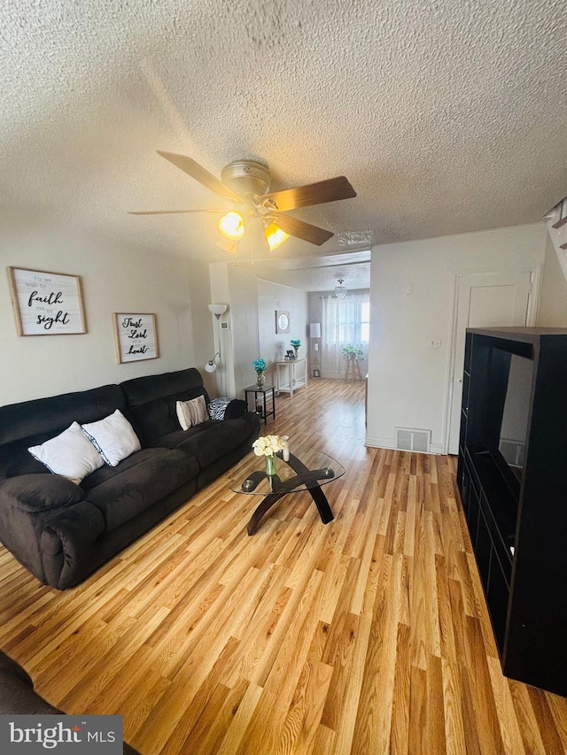 living room with visible vents, ceiling fan, a textured ceiling, and light wood-style flooring