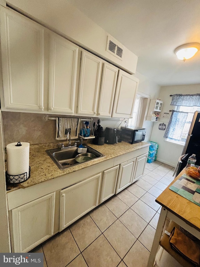 kitchen featuring light tile patterned floors, baseboards, visible vents, light countertops, and a sink