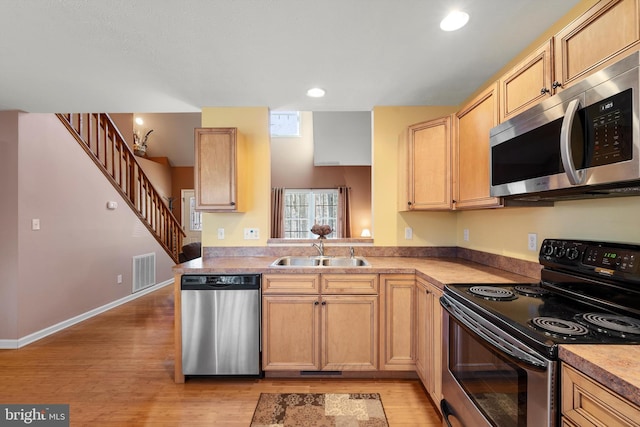 kitchen with visible vents, appliances with stainless steel finishes, light brown cabinets, a sink, and light wood-type flooring