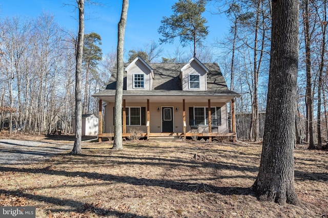 new england style home featuring a shed, a porch, and an outdoor structure