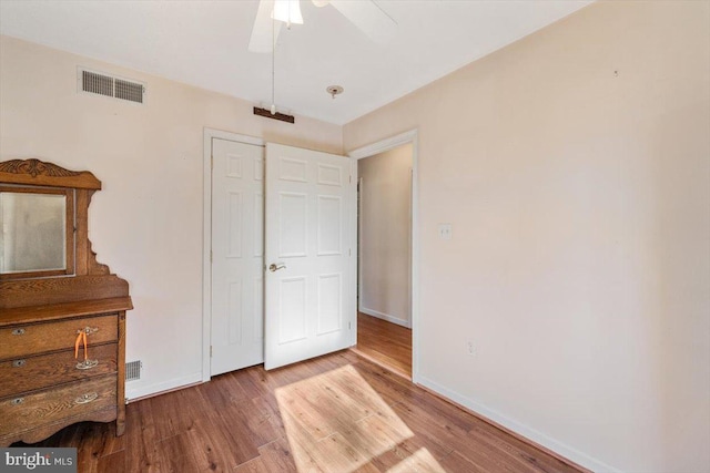 unfurnished bedroom with visible vents, ceiling fan, baseboards, and wood finished floors