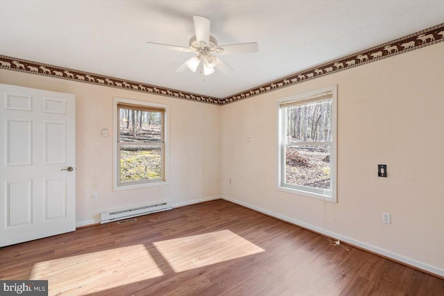 empty room with baseboard heating, wood finished floors, and a healthy amount of sunlight