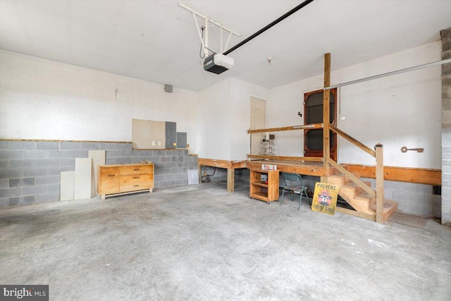 garage featuring a garage door opener, concrete block wall, and a workshop area