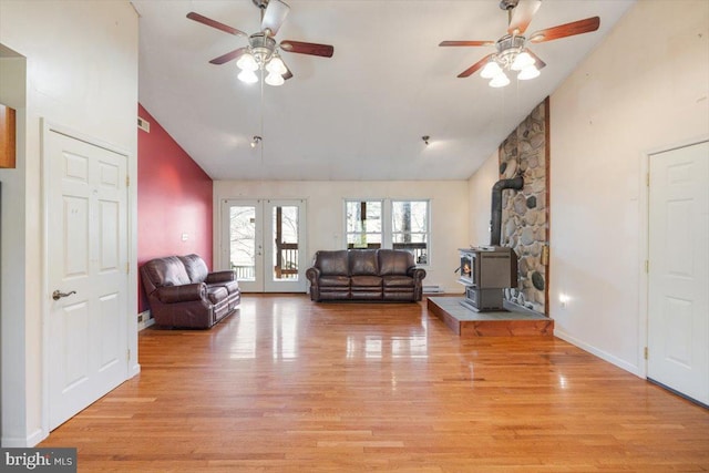 living area with light wood-style floors, french doors, high vaulted ceiling, and a wood stove