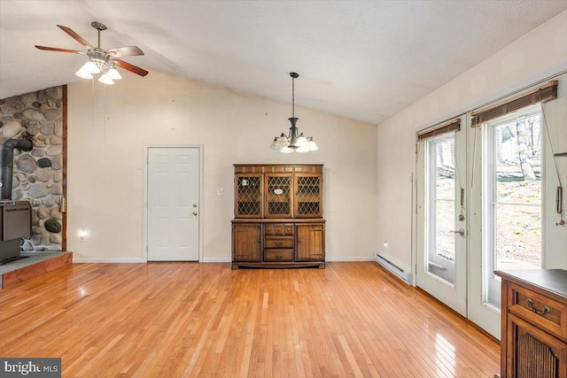 unfurnished dining area with lofted ceiling, baseboards, light wood-style floors, baseboard heating, and a wood stove