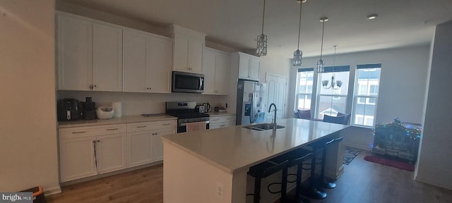 kitchen with an island with sink, white cabinets, stainless steel appliances, and a sink