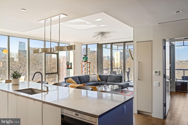 kitchen featuring a wall of windows, white cabinets, a sink, and decorative light fixtures