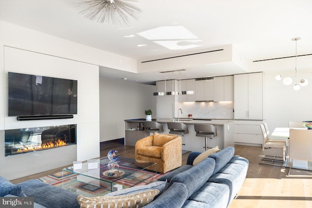 living area featuring a glass covered fireplace, light wood-style flooring, and an inviting chandelier