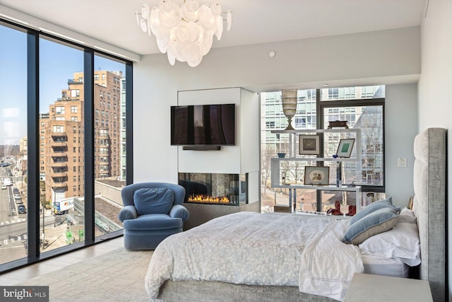 bedroom featuring a lit fireplace and a wall of windows