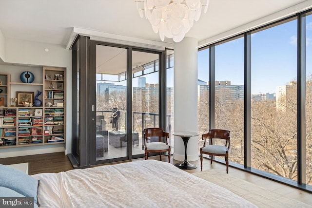 bedroom featuring a view of city, access to outside, expansive windows, and wood finished floors