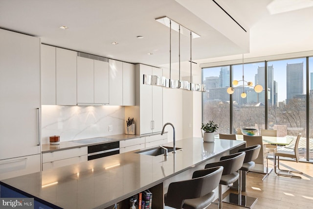 kitchen with white cabinets, modern cabinets, a city view, and a sink