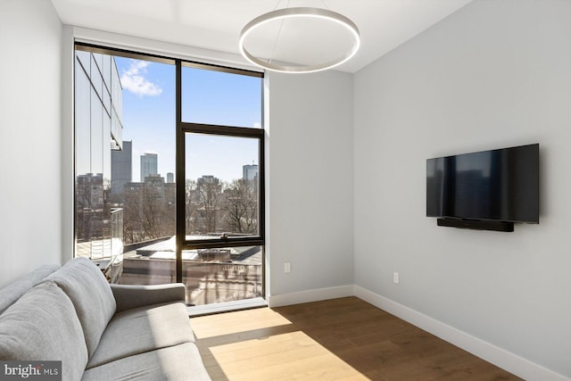 living room featuring baseboards, floor to ceiling windows, and wood finished floors