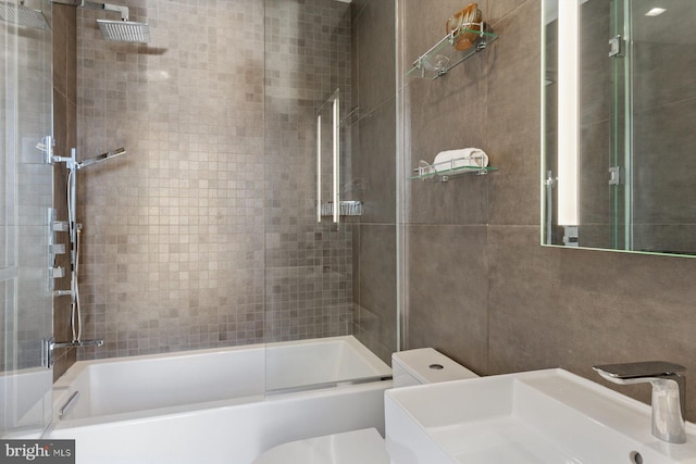 bathroom featuring combined bath / shower with glass door, a sink, and toilet