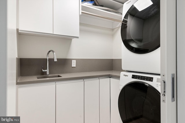 clothes washing area with stacked washer and dryer, a sink, and cabinet space