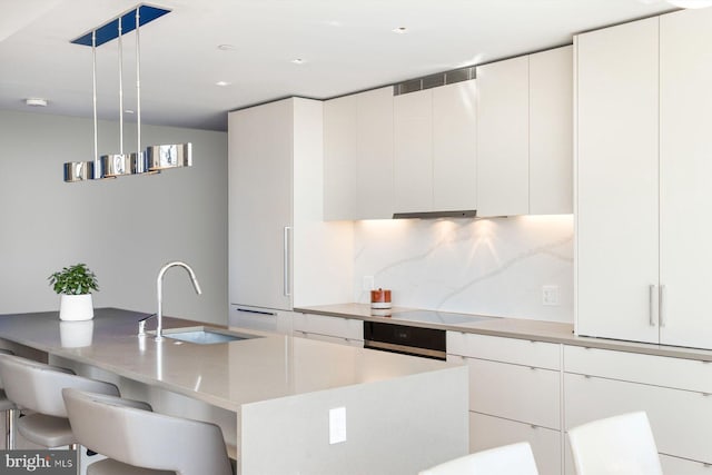 kitchen featuring hanging light fixtures, white cabinets, and a sink