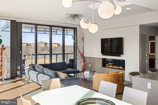 dining space with a wall of windows, wood finished floors, and a glass covered fireplace