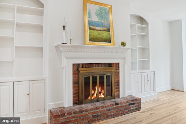 room details with a brick fireplace, built in features, wood finished floors, and baseboards