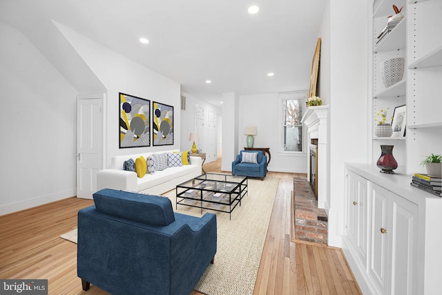 living room with a brick fireplace, recessed lighting, light wood-style floors, and baseboards