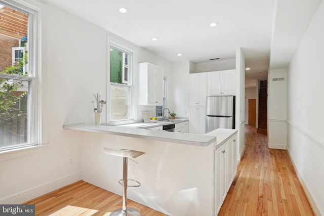 kitchen featuring plenty of natural light, light wood-style flooring, appliances with stainless steel finishes, and white cabinets