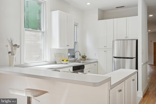 kitchen featuring visible vents, a sink, white cabinetry, stainless steel appliances, and light countertops