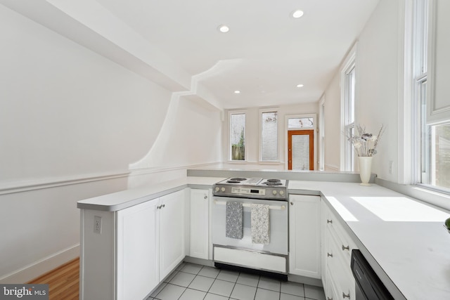 kitchen with a wealth of natural light, range with electric cooktop, white cabinets, and light countertops