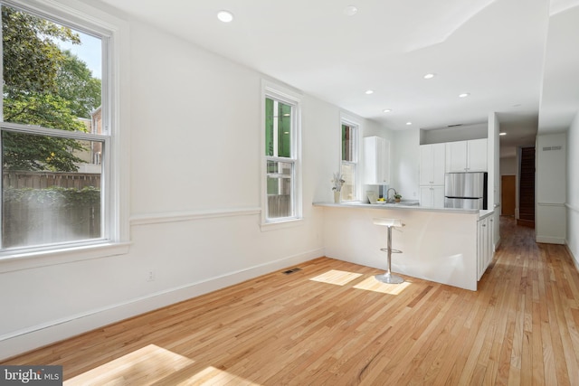 kitchen featuring light wood-style flooring, recessed lighting, white cabinets, and freestanding refrigerator