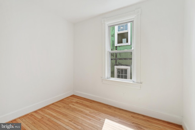 spare room with baseboards and hardwood / wood-style floors