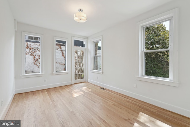 unfurnished room featuring baseboards, visible vents, and light wood finished floors