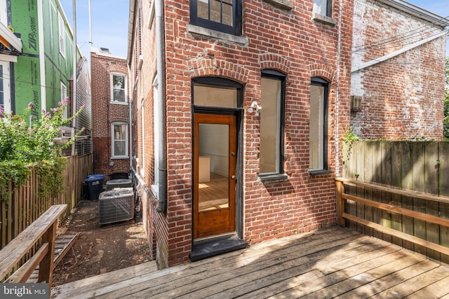 property entrance featuring brick siding, a deck, and fence