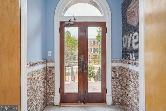 doorway with a wainscoted wall, french doors, and tile walls