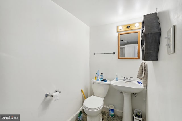 half bathroom with a sink, baseboards, and toilet