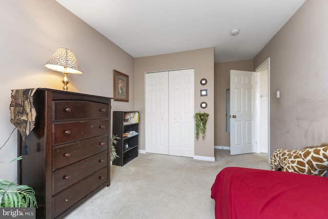 bedroom with baseboards, a closet, and light colored carpet