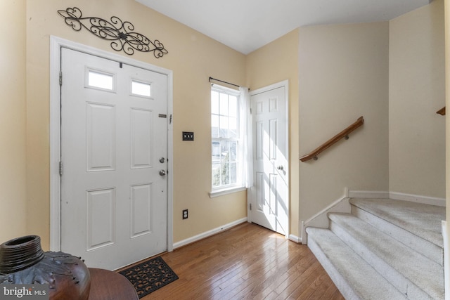 foyer entrance with wood-type flooring, stairway, and baseboards