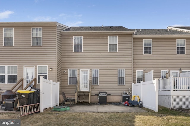 rear view of property with entry steps, a lawn, and fence