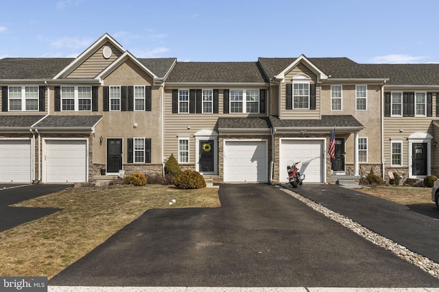 townhome / multi-family property featuring driveway, a garage, a shingled roof, stone siding, and stucco siding