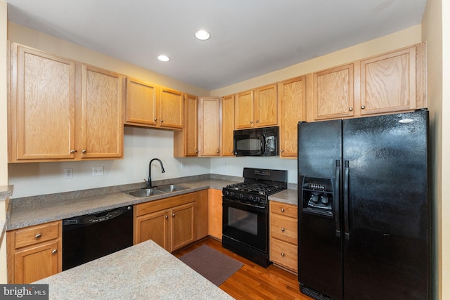 kitchen with recessed lighting, light brown cabinets, a sink, wood finished floors, and black appliances