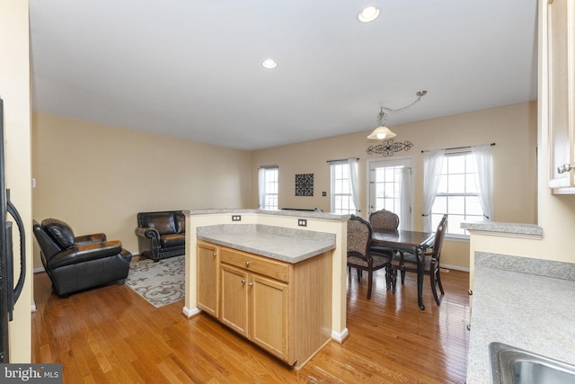 kitchen with recessed lighting, a sink, light wood-style floors, open floor plan, and light countertops