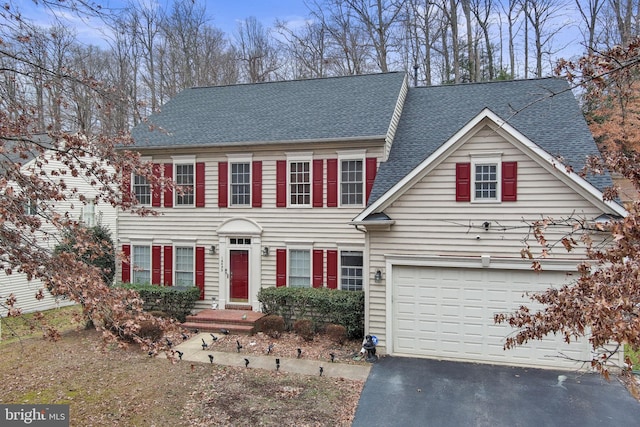 colonial home with aphalt driveway and a shingled roof