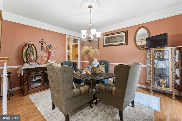 dining room featuring a chandelier, ornamental molding, wood finished floors, and baseboards