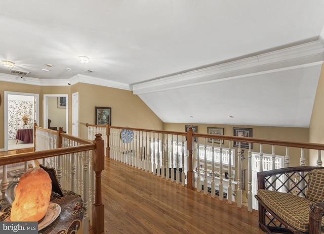 hallway featuring lofted ceiling, ornamental molding, wood finished floors, and visible vents