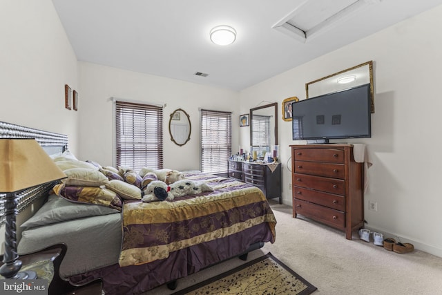 carpeted bedroom with baseboards, visible vents, and attic access