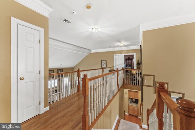 hall with ornamental molding, wood finished floors, and an upstairs landing