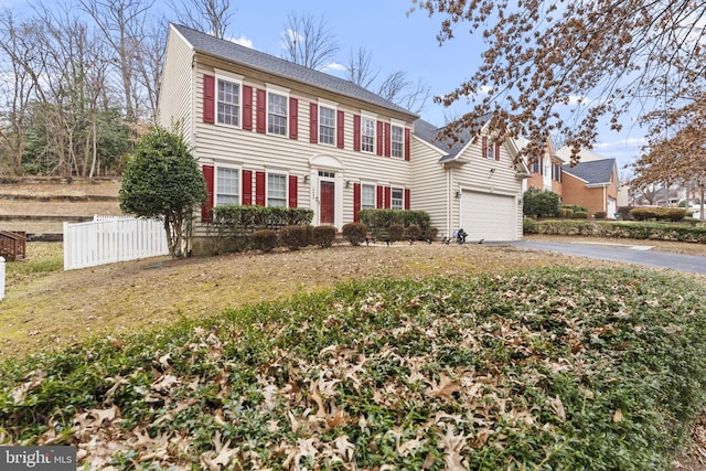 colonial-style house with a garage, fence, and driveway