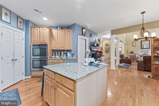 kitchen featuring decorative columns, double oven, light wood-style floors, open floor plan, and light brown cabinets