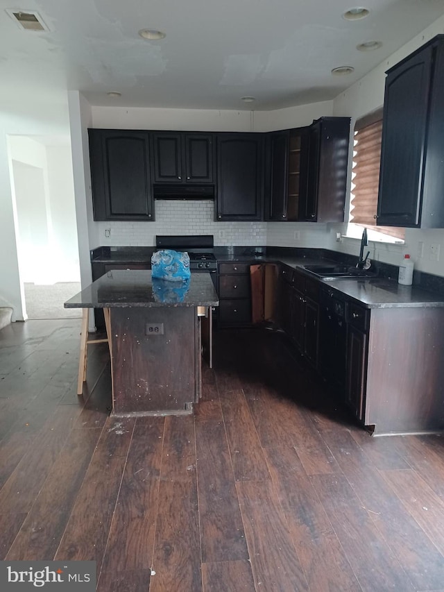 kitchen with dark wood-style flooring, visible vents, backsplash, a sink, and under cabinet range hood