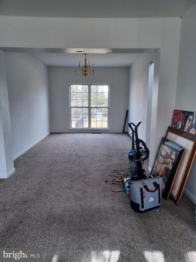 unfurnished living room with a chandelier, carpet flooring, and baseboards