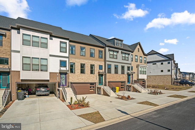 multi unit property featuring an attached garage, a residential view, concrete driveway, and brick siding